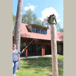 A woman pulling a rope attached to a bell on a pole