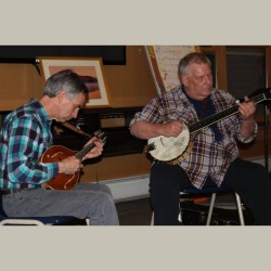 Two men sitting next to each other playing instruments