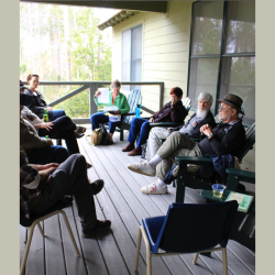 A group of people sitting on a porch and talking
